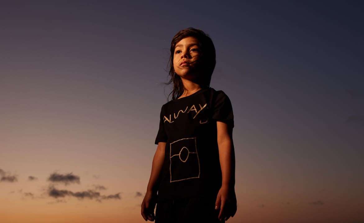 Young girl standing tall and proud, looking into the distance at sunset.