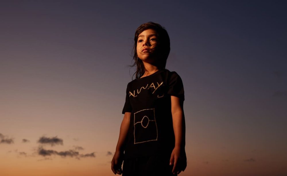 Young girl standing tall and proud, looking into the distance at sunset.